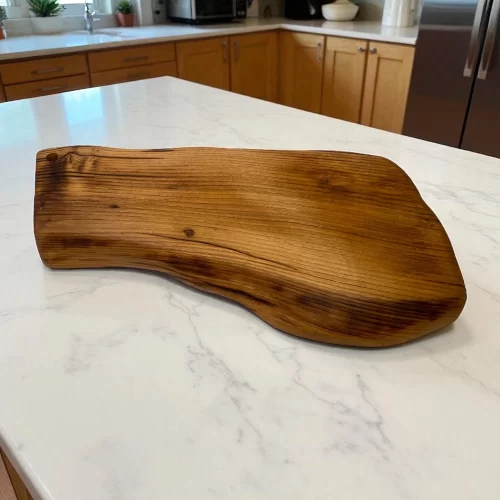 Irregular solid wood cutting board with hanging hole, ideal for serving and cutting food in the kitchen.