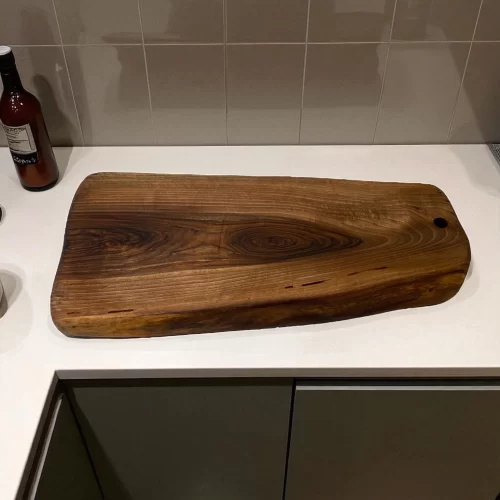 Tagliere irregolare in legno massello con foro per appenderlo, ideale per servire e tagliare alimenti in cucina.