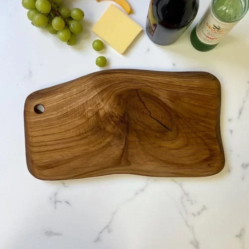 Irregular solid wood cutting board with hanging hole, ideal for serving and cutting food in the kitchen.