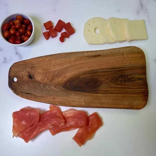Irregular solid wood cutting board with hanging hole, ideal for serving and cutting food in the kitchen.