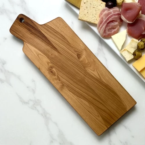 Tagliere artigianale rettangolare con manico in legno massello levigato a mano con foro per appenderlo, ideale per servire aperitivi e tagliare alimenti.