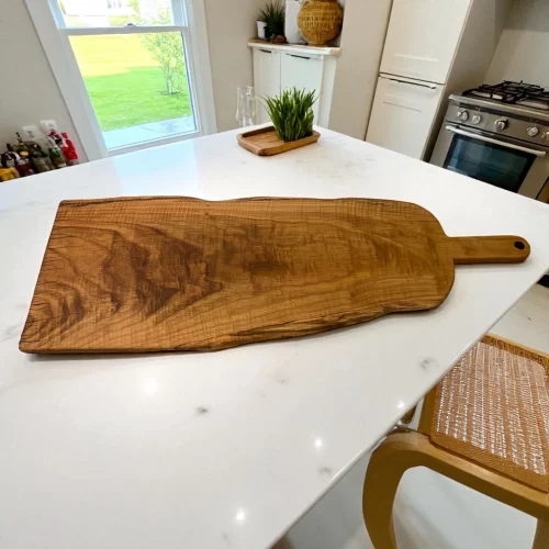 Tagliere artigianale di grande dimensione in legno massello lavorato a mano, con foro per appenderlo, ideale per servire salumi, formaggi e antipasti.