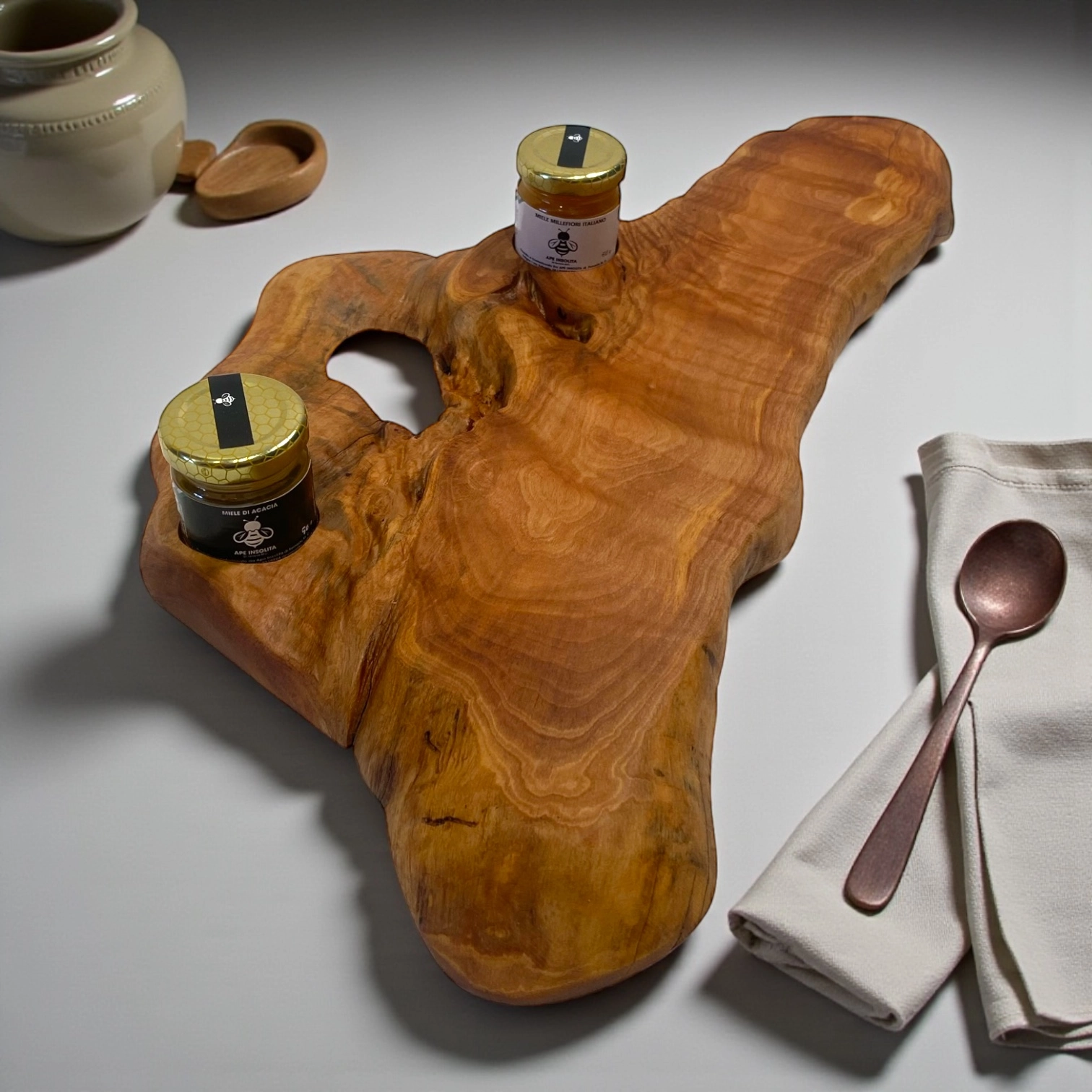 Tagliere artigianale in legno di ulivo con due barattoli di miele dell’Umbria su vassoio naturale